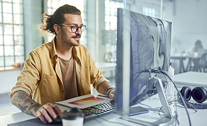picture of a man with long hair and glasses sitting in front of a computer